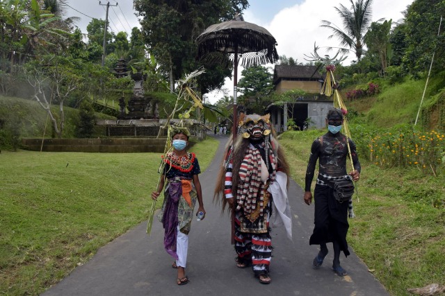 Tiga warga menggunakan masker saat turut berkeliling kampung dalam tradisi Ngerebeg di Desa Tegallalang, Gianyar. Foto: Nyoman Hendra Wibowo/ANTARA FOTO