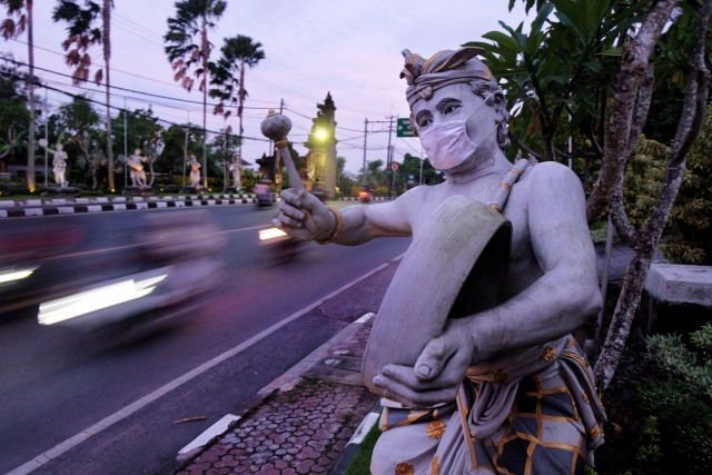 Sebuah patung seniman menggunakan masker di Badung. Foto: Nyoman Hendra Wibowo/ANTARA FOTO