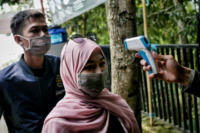 Pengunjung diperiksa suhu tubuh saat masuk gerbang tempat wisata Tebing Keraton, Kecamatan CImenyan, Kabupaten Bandung, Jawa Barat, Minggu (1/11/2020). Foto: Jamal Ramadhan/kumparan