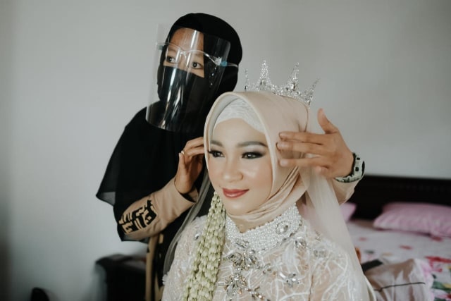 Nicka Savitri (33) lengkap menggunakan face shield dan masker saat merias salah satu pengantin. Foto: Nicka Makeup Studio Kota Batu.
