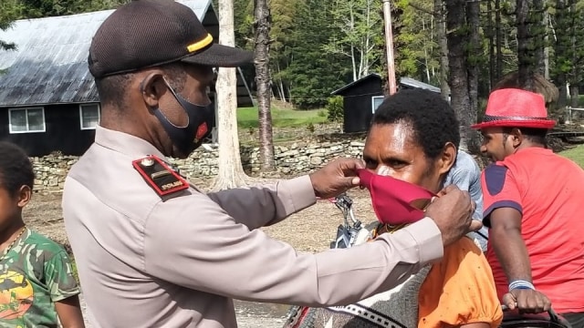 Polisi di Bokondini menggunakan masker kepada warga setempat. (Dok Polda Papua)