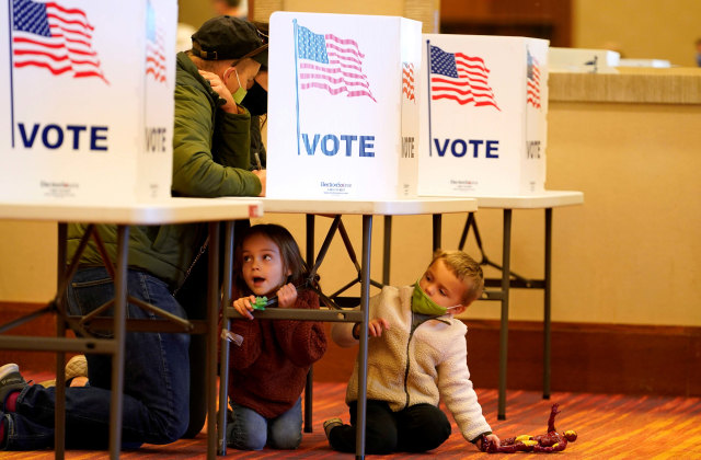 Anak ikut orang tua memberikan suara pada Pemilu AS di Jeffersontown, Kentucky, AS, Selasa (3/11). Foto: BRYAN WOOLSTON/REUTERS