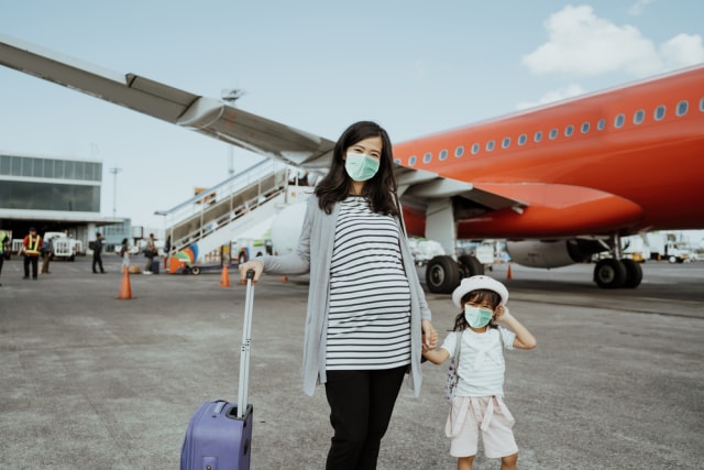 Anak pakai masker naik pesawat saat pandemi. Foto: Shutterstock