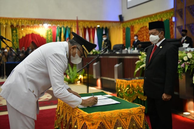 Nova Iriansyah menandatangai berita acara saat pelantikan di Gedung DPR Aceh, Kamis (5/11). Foto: Humas Setda Aceh
