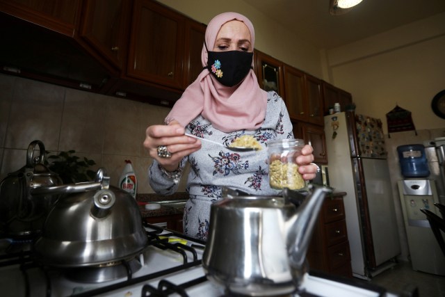 Randa Amar menyiapkan jamu untuk keluarganya di Amman, Yordania, Rabu (4/11).  Foto: Muhammad Hamed / REUTERS