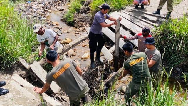Personel polisi di Distrik Sinak, Kabupaten Puncak Papua memperbaiki jembatan penghubung antar distrik. (Dok Polda Papua)