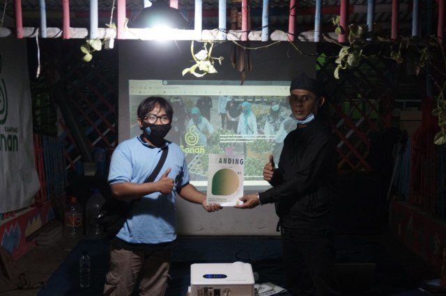 Ketua RW 15 Kampung Sanan, Ivan Kuncoro, saat menerima buku panduan grafis wisata (tourism map) bikinan anak mahasiswa DKV UM, Sabtu (8/11) malam. Foto: KKN Sedesa UM