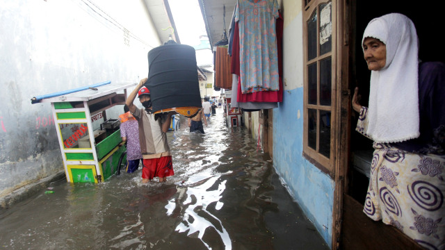 Warga berjalan melewati banjir yang melanda permukiman di Kemang Utara, Jakarta, Minggu (8/11). Foto: Reno Esnir/ANTARA FOTO