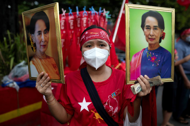 Seorang pendukung Liga Nasional untuk Demokrasi (NLD) memegang dua foto Aung San Suu Kyi ketika merayakan kemenangan di markas partai di Yangon, Myanmar. Foto: Shwe Paw Mya Tin/Reuters