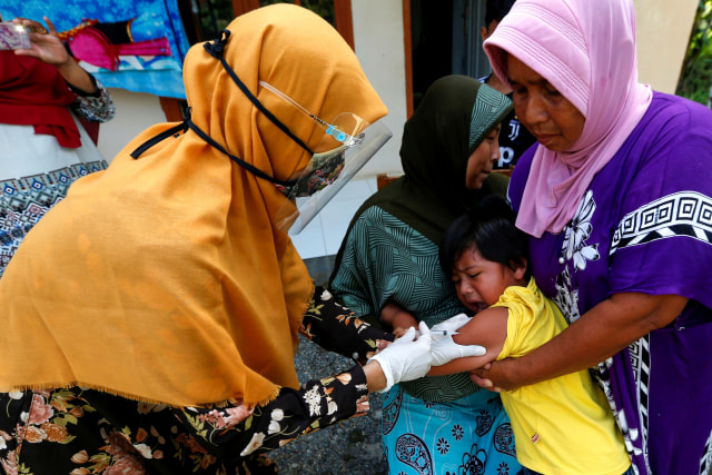 Petugas kesehatan Puskesmas Ulee Kareng (kiri) menyuntikkan vaksin imunisasi kepada balita di rumahnya di Desa Ilie, Banda Aceh, Aceh. Foto: Irwansyah Putra/ANTARA FOTO
