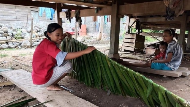 Suasana Deli, seorang ibu rumah tangga di Tolitoli, membuat atap rumbia di bawah kolom rumahnya. Foto: Moh. Sabran/PaluPoso