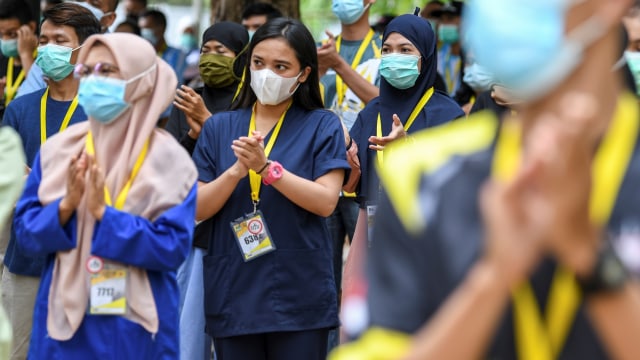 Sejumlah tenaga kesehatan dan non tenaga kesehatan bertepuk tangan saat menghadiri peringatan Hari Kesehatan Nasional (HKN) ke-56 di Rumah Sakit Darurat COVID-19 Wisma Atlet Kemayoran di Jakarta, Kamis (12/11). Foto: M Risyal Hidayat/ANTARA FOTO