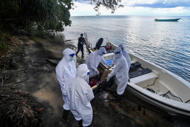 Petugas kesehatan dari EcoNusa Foundation menaikkan warga yang diduga terpapar COVID-19 ke atas kapal saat simulasi penanganan pasien terpapar COVID-19 di Pulau Hatta, Banda, Maluku, Sabtu (14/11). Foto: Muhammad Adimaja/ANTARA FOTO