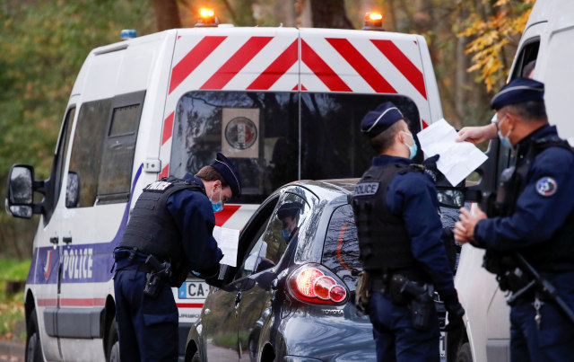 Suasana saat Polisi Prancis menghentikan mobil untuk memeriksa dokumen pengecualian dan identitas saat lockdown di daerah Bois de Boulogne, di Paris, Prancis. Foto: Christian Hartmann/Reuters