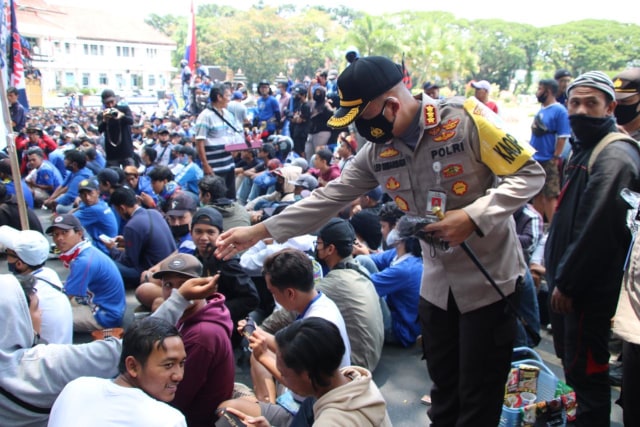 Kapolresta Malang Kota, Kombes Pol Leonardus Simarmata, saat membagikan masker kepada Aremania yang menuntut penuntasan konflik dualisme Arema di depan Kantor DPRD Kota Malang, pada Senin (16/11/2020). Foto: Ulul Azmy