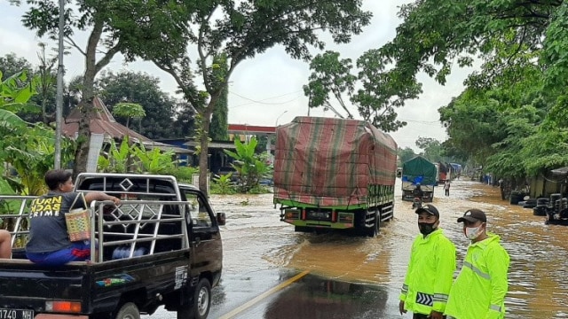 Petugas Polresta Banyumas mengatur lalu lintas kendaraan di ruas jalan nasional Buntu-Sumpiuh yang tergenang banjir pada Selasa (17/11). Foto: Sumarwoto/ANTARA