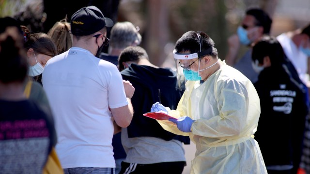 Anggota staf medis mendata orang-orang yang mengantre di lokasi pengujian virus corona, di Adelaide, Australia, Selasa (17/11). Foto: AAP/Kelly Barnes via REUTERS
