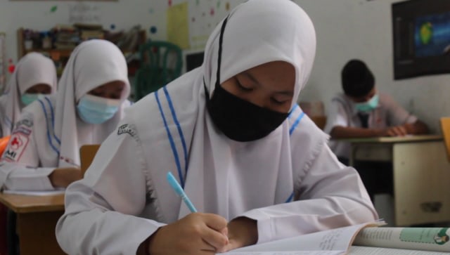 SEORANG siswa kelas IX SMPN 3 Pekanbaru mengenakan masker saat hari pertama proses belajar-mengajar secara tatap muka di Pekanbaru.