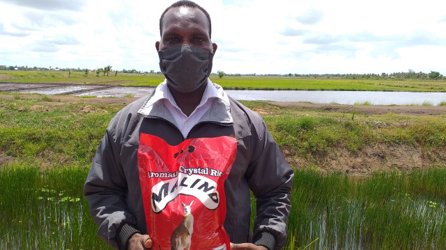 Iranius Yawa, memperlihatkan beras dengan merk Malind, hasil keringat petani milenial asal Merauke Papua. (BumiPapua.com/Abdel Syah)