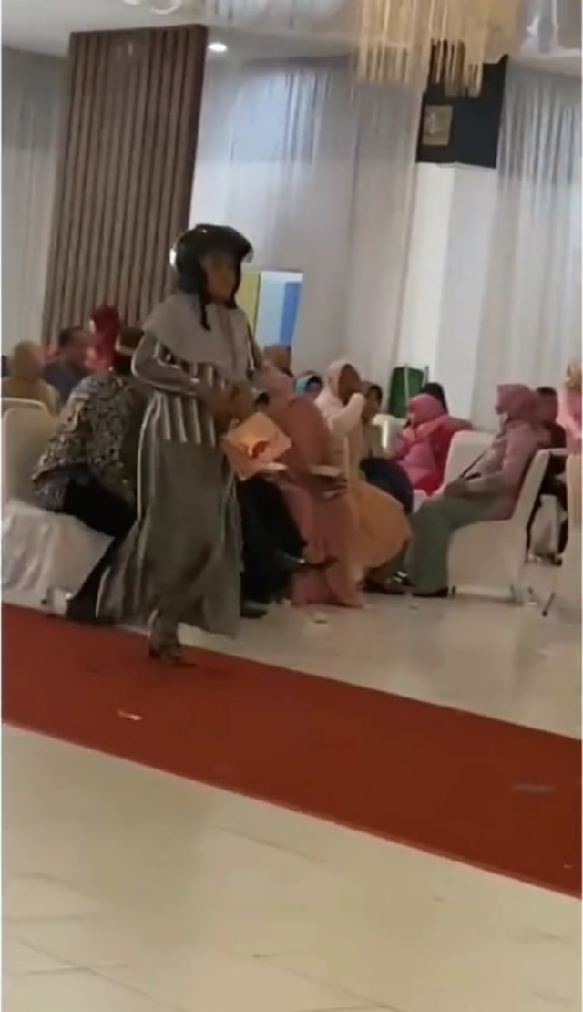 Viral aksi kocak seorang emak-emak di Makassar pakai helm ke kondangan. (Foto: Instagram/@makassar_iinfo)