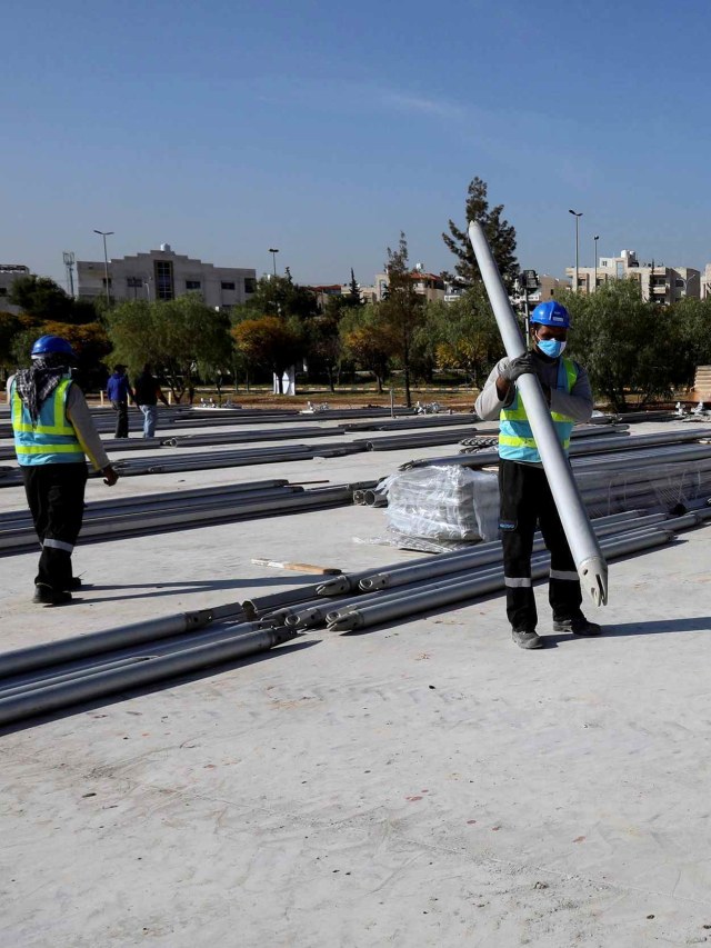 Pekerja memindahkan bahan bangunan untuk rumah sakit darurat di lapangan gedung rumah sakit pemerintah Pangeran Hamzah, di Amman, Yordania. Foto: Muhammad Hamed/Reuters