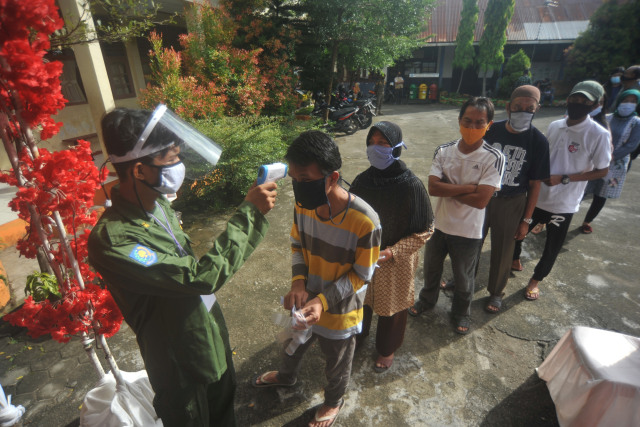 Petugas KPPS mengecek suhu tubuh calon pemilih saat simulasi pemilihan serentak di Padang, Sumatera Barat, Sabtu (21/11). Foto: Iggoy el Fitra/ANTARA FOTO