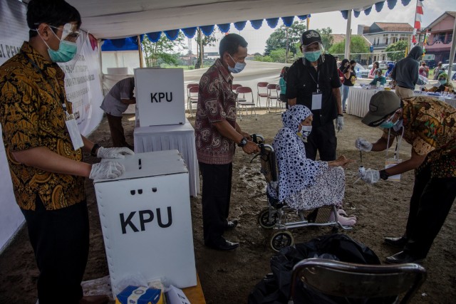 Petugas membantu warga lanjut usia mengikuti simulasi pemungutan suara Pilkada Kabupaten Bandung 2020 di TPS 109, Baleendah, Kabupaten Bandung, Jawa Barat, Sabtu (21/11). Foto: Novrian Arbi/ANTARA FOTO