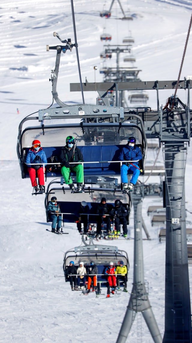 Sejumlah pengunjung yang mengenakan masker duduk di lift ski sebelum meluncur di atas salju, di resor ski Zermatt, Swiss. Foto: Denis Balibouse/REUTERS
