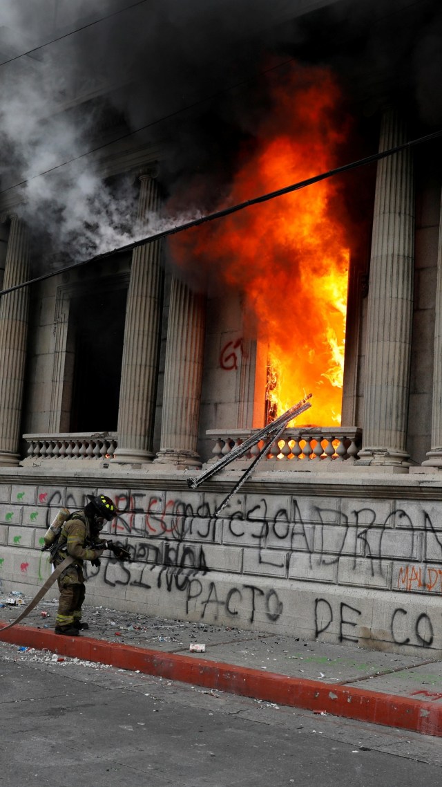 Petugas pemadam kebakaran memadamkan api di kantor gedung Kongres yang dibakar massa saat protes menuntut pengunduran diri Presiden Alejandro Giammattei, di Guatemala City, Guatemala, Sabtu (21/11). Foto: Luis Echeverria/REUTERS