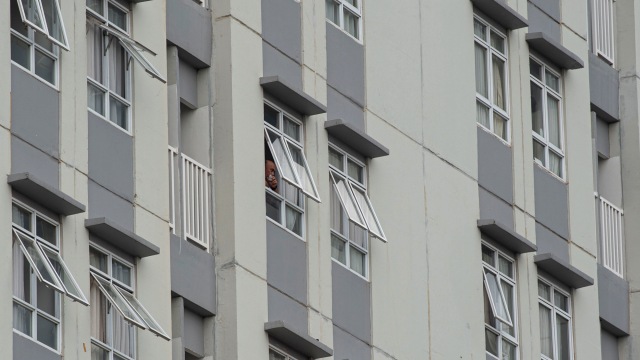 Pasien mengintip suasana luar gedung dari balik jendela ruang perawatan di Rumah Sakit Darurat COVID-19 Wisma Atlet Kemayoran, Jakarta, Senin (23/11). Foto: Aditya Pradana Putra/ANTARA FOTO