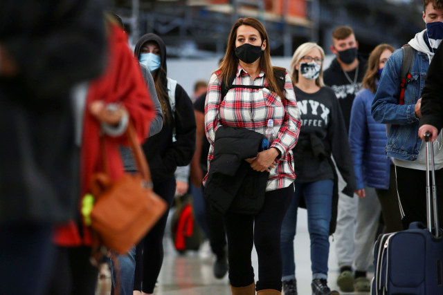 Wisatawan memakai masker saat mereka tiba di bandara di Denver, Colorado, Amerika Serikat. Foto: Kevin Mohatt/Reuters
