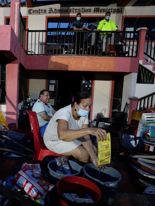 Pemilik supermarket yang memakai masker saat mencuci barang dagangan yang bisa dia simpan usai Badai Iota di Providencia, Kolombia. Foto: Nathalia Angarita/Ruters