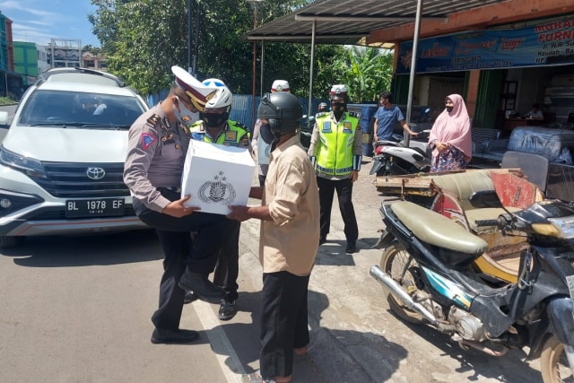 Personel Polantas Polda Aceh membagikan masker dan paket sembako untuk tukang becak di Banda Aceh. Foto: Ditlantas Polda Aceh