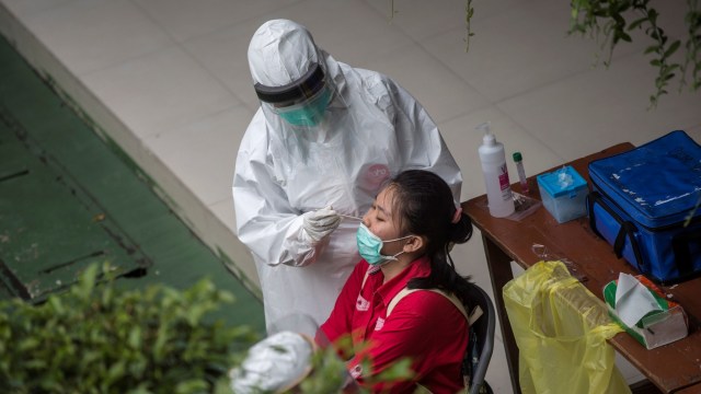 Seorang petugas medis mengambil sampel dari seorang siswa sekolah menengah untuk menguji virus Corona, di Surabaya. Foto: AFP/JUNI KRISWANTO