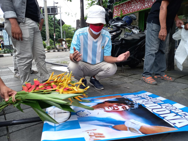 Caka Boda, penggemar sepak bola membawa sebuah karangan bunga dan poster bertuliskan Rest in Peace Maradona di perempatan lampu merah Ngarsopuro, Solo, Kamis (26/11)