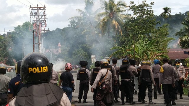 Anggota kepolisian menembakkan gas air mata kearah massa aksi yang melakukan aksi pelemparan batu dan botol kaca, foto : Yanti