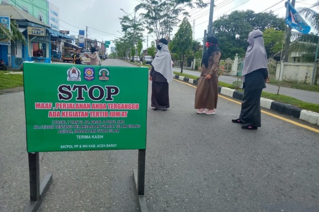 Personel perempuan Satpol PP-WH Aceh Barat atau polisi syariat dibantu polisi wanita saat menutup ruas jalan selama salat Jumat berlangsung. Foto: Siti Aisyah/acehkini