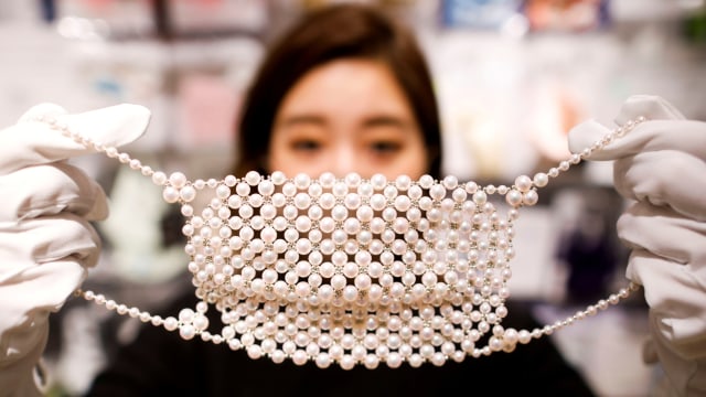 Karyawan menunjukkan masker wajah yang terbuat dari sekitar 330 mutiara di Tokyo, Jepang.  Foto: Issei Kato/REUTERS