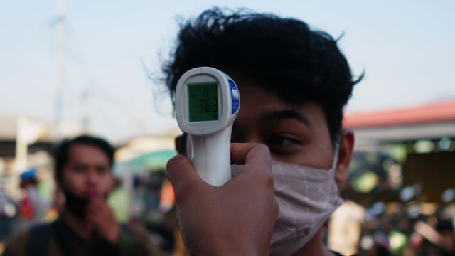Ilustrasi pemeriksaan suhu tubuh dengan thermo gun. Foto: Jamal Ramadhan/kumparan