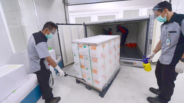 Petugas menyemprotkan disinfektan ke kontainer berisi vaksin COVID-19 Sinovac saat tiba di Bio Farma, Bandung, Jawa Barat. Foto: Muchlis Jr/Biro Pers Sekretariat Presiden