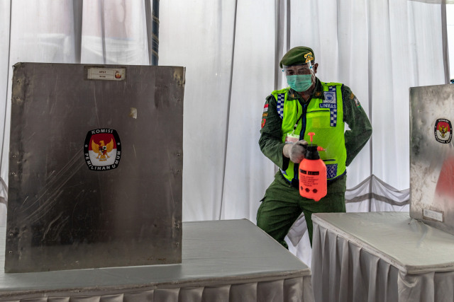 Petugas menyemprotkan cairan disinfektan ke area Tempat Pemungutan Suara (TPS) saat simulasi pemungutan suara Pilkada 2020 di Bergas, Kabupaten Semarang, Jawa Tengah. Foto: Aji Styawan/ANTARA FOTO