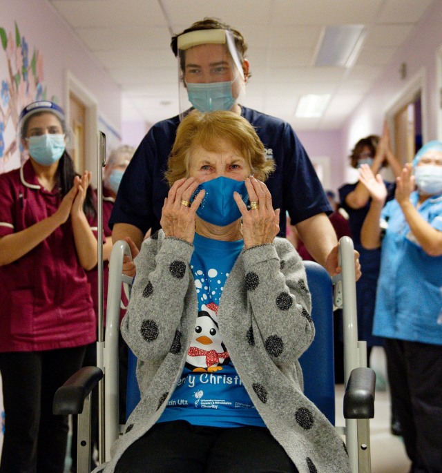 Margaret Keenan mendapat tepuk tangan dari staf rumah sakit setelah menjadi pasien pertama di Inggris yang menerima vaksin corona Pfizer BioNtech COVID-19 di Rumah Sakit Universitas, Coventry, Inggris. Foto: Jacob King / Pool / REUTERS
