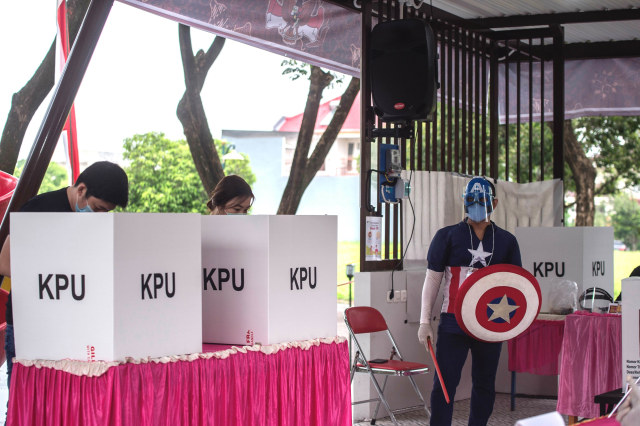 Petugas berkostum Captain America berjaga di TPS 14, Perumahan Citraland, Surabaya, Jawa Timur, Rabu (9/12). Foto: Juni Kriswanto / AFP
