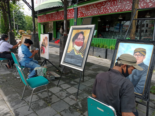 Sambut kemenangan Gibran, 5 pelukis dari Kelompok Pelukis Solo sedang asyik melukis potret wajah Gibran di trotoar jalan perempatan Ngarsopuro, Surakarta, Kamis (10/12)