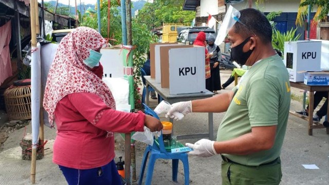 Petugas KPPS di salah TPS di Padang melakukan pengukuran suhu tubuh kepada pemilih yang datang ke TPS pada Pilkada Serentak 200. Foto: ist