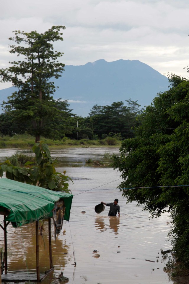 Warga berjalan melintasi banjir yang menggenangi permukiman di Kampung Sewu, Jebres, Solo, Jawa Tengah, Senin (14/12/2020). Foto: Maulana Surya/ANTARA FOTO