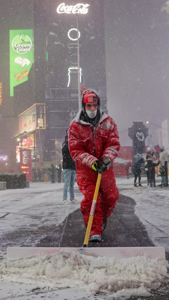 Seorang pekerja membersihkan salju saat salju mulai turun di Times Square selama Nor'easter, di Manhattan, New York City, AS, (16/12). Foto: Jeenah Moon/REUTERS