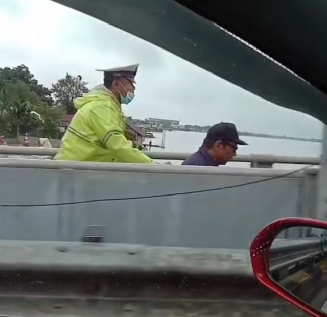 Anggota Unit Lalulintas, Polsek Pontianak Utara, Briptu Budi Irawan, mendorong warga difabel berkursi roda yang hendak melintas di jembatan landak Pontianak. Foto: Dok Hi!Pontianak 