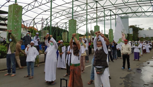 Massa aksi Muslim Malang Bersatu mengepalkan tangan terborgol sebagai aksi solidaritas menuntut pembebasan Habib Rizieq Shihab, pada Jumat (18/12/2020). Foto: Ulul Azmy