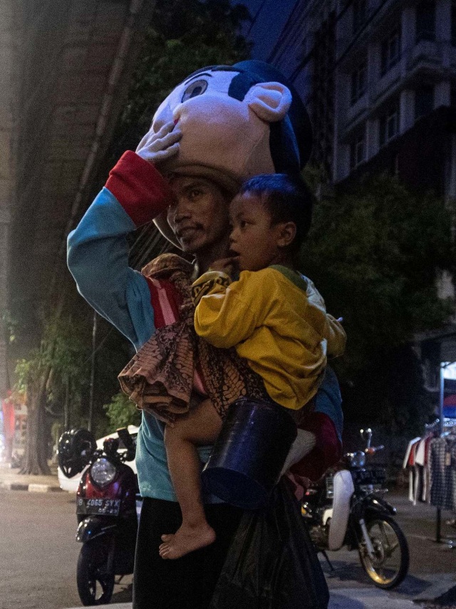 Wahyu menggendong anaknya sambil mengamen sebagai badut di Jalan Pangeran Antasari, Jakarta Selatan. Foto: Sigid Kurniawan/Antara Foto